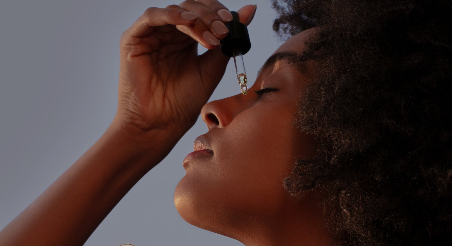 A lady dropping face oil.